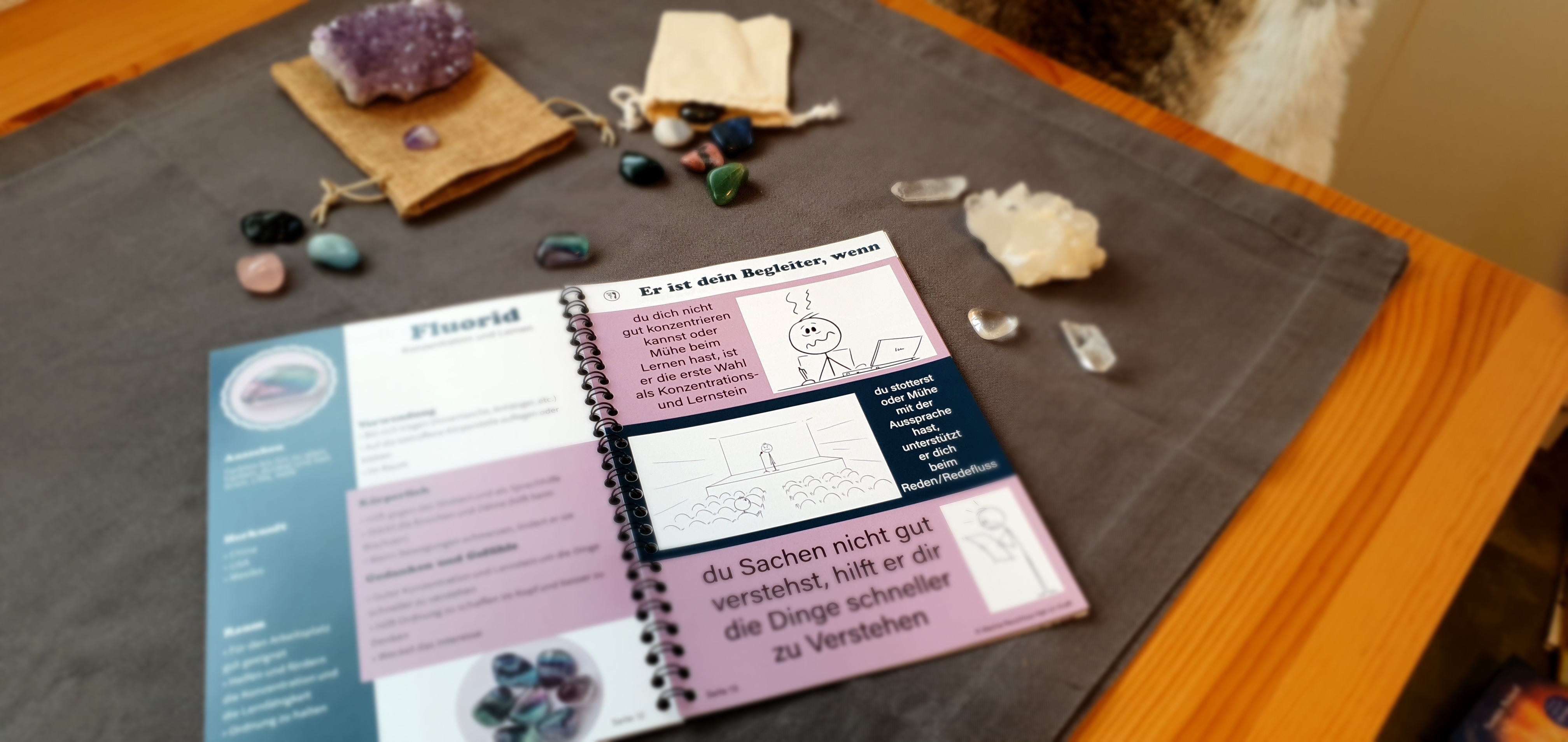 Auf einem Tisch ist das Kursbuch und die sieben verschiedenen Heilsteine