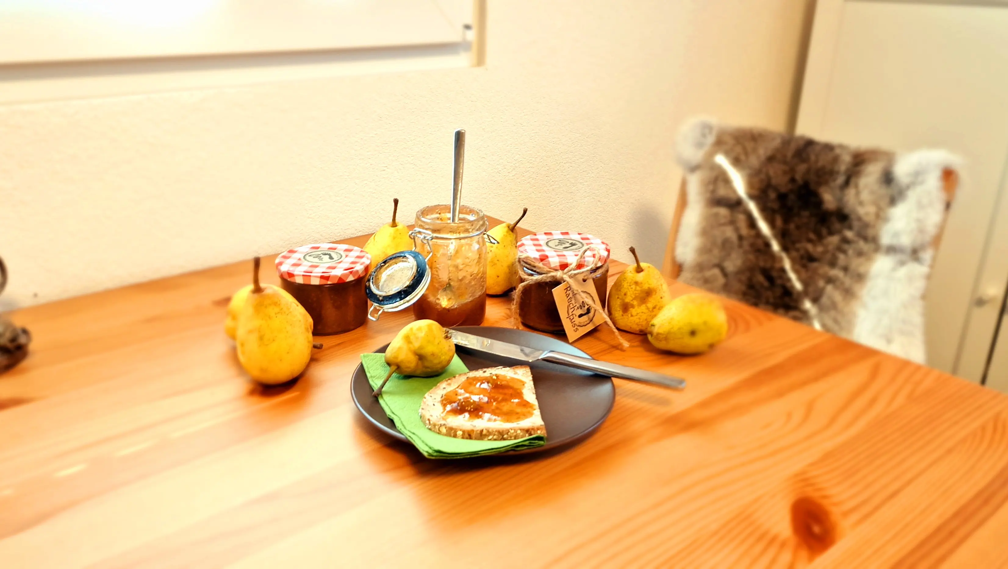 Ein Holztisch mit 4 verschiedenen grössen von Einmachgläsern, ein Teller mit einem Brombeerkonfitürebrot und dekoriet mit frischen Brombeeren und deren Blätter