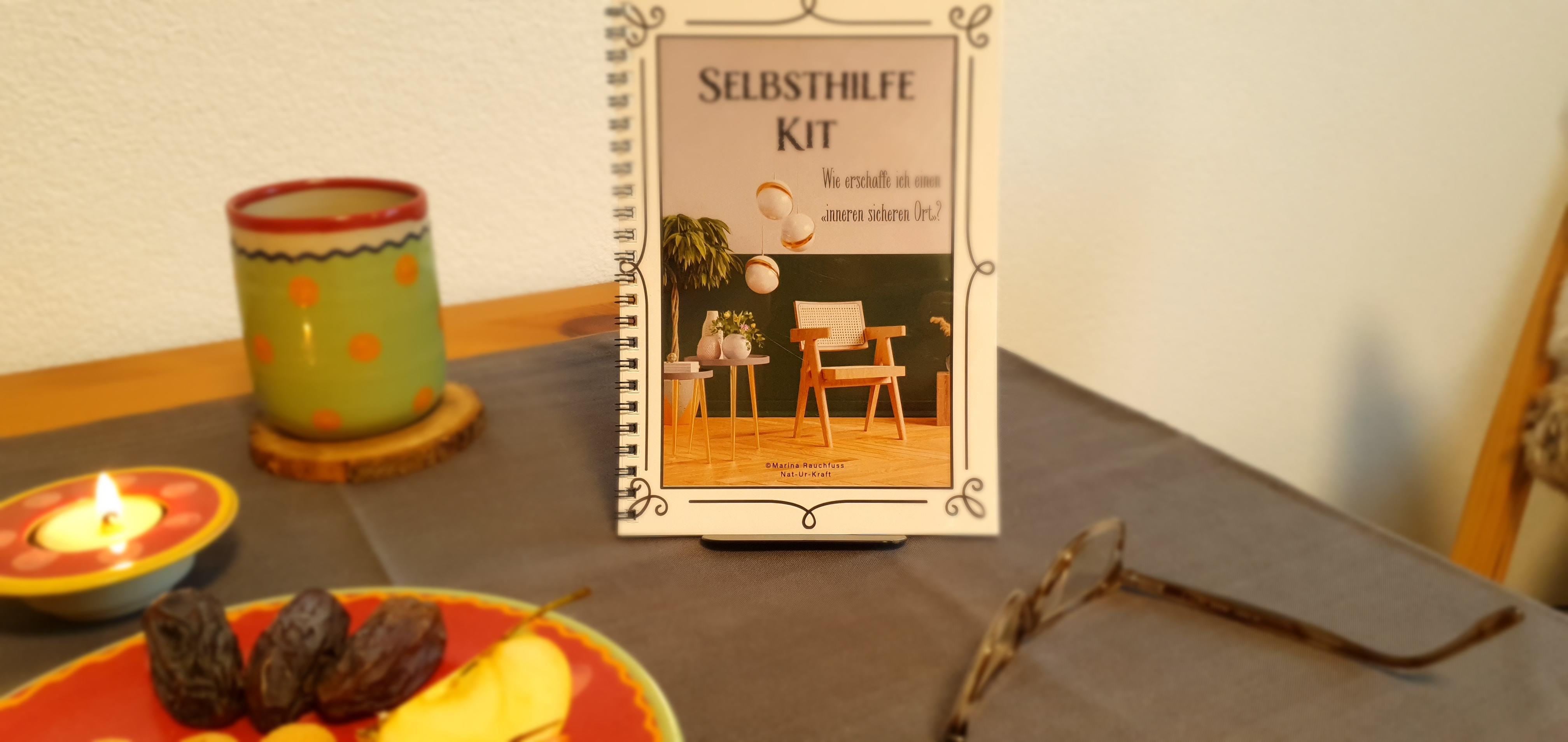Auf einem Tisch ist das Kursbuch und die sieben verschiedenen Heilsteine